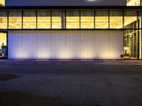 a very large white building lit by some lights from outside the windows as people walk by it