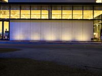 a very large white building lit by some lights from outside the windows as people walk by it