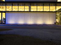 a very large white building lit by some lights from outside the windows as people walk by it