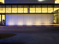 a very large white building lit by some lights from outside the windows as people walk by it