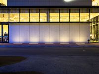 a very large white building lit by some lights from outside the windows as people walk by it