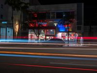 a street with a lit store on the side of it at night next to some tall buildings