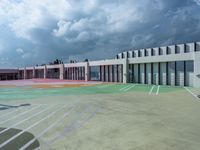 a parking lot that has some big windows and some cars in front of it, on top of a cloudy sky