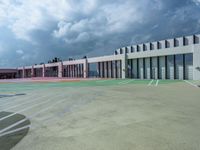 a parking lot that has some big windows and some cars in front of it, on top of a cloudy sky