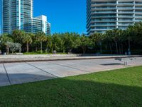 this concrete park features a bench in front of tall buildings and plants surrounding the space