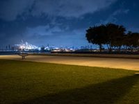 a bench overlooking the water with a big city skyline in the background at night time