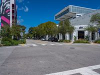 empty city street with several cars parked on the side of it and a red sign in front