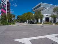 empty city street with several cars parked on the side of it and a red sign in front