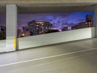 an empty parking garage has the city lights on at night, all painted white and purple