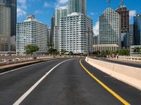 the empty road with lots of skyscrapers in the background with cars driving on the roadway