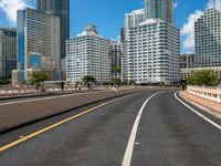 this is a picture of the empty freeway in the city with many skyscrapers in the background