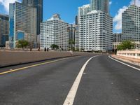 this is a picture of the empty freeway in the city with many skyscrapers in the background