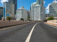 this is a picture of the empty freeway in the city with many skyscrapers in the background