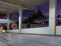 a view of a busy city street at night from an underground parking garage space, with a blue light from above