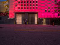 a large building that is red lit up at night with a red light shining on the side