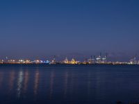 the skyline lights up in the blue night sky in this wide view of a harbor