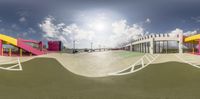 a view of a tennis court with different ramps and stairs in the background and clouds overhead