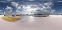 a skate board is seen from below, and the ground is dirt - like, while a street view of skyscrapers are beyond