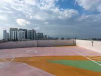 an empty playground in a city with multiple colors on the ground and cloudy skies above