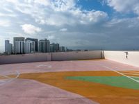 an empty playground in a city with multiple colors on the ground and cloudy skies above