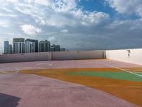 an empty playground in a city with multiple colors on the ground and cloudy skies above