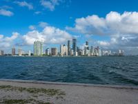 a beach has water in front of buildings that have windows to see the city's skylines