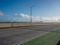 a green area next to a highway next to the ocean with an overpass and street lights on a sunny day