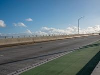 a bus is travelling on an empty highway with clouds behind it in the distance,