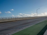 a bus is travelling on an empty highway with clouds behind it in the distance,