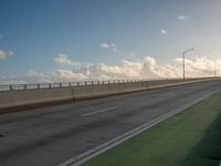 a bus is travelling on an empty highway with clouds behind it in the distance,