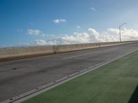 a bus is travelling on an empty highway with clouds behind it in the distance,