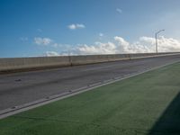 a bus is travelling on an empty highway with clouds behind it in the distance,