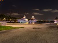 two boats docked next to each other in a marina at night time, with some lights on