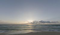 some waves that are in the sand next to the water on a beach at sunset