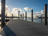 boats are moored at the harbor near a pier with posts sticking out into the water