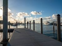 boats are moored at the harbor near a pier with posts sticking out into the water