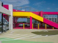 an empty parking lot with brightly painted stairs leading to a large open area for pedestrians to walk by
