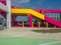 an empty parking lot with brightly painted stairs leading to a large open area for pedestrians to walk by