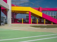 an empty parking lot with brightly painted stairs leading to a large open area for pedestrians to walk by