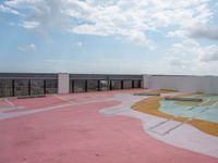 a large concrete parking lot on top of a building that has a colorful design on the floor