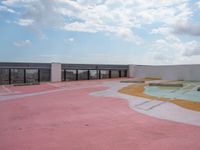 a large concrete parking lot on top of a building that has a colorful design on the floor