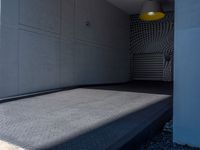 a gray walkway leading up to a building next to a yellow light lantern on top