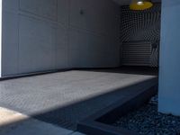 a gray walkway leading up to a building next to a yellow light lantern on top