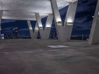 the concrete structure in the center of an empty area at night shows the city's silhouettes