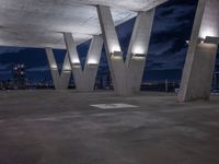 the concrete structure in the center of an empty area at night shows the city's silhouettes