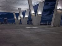 the concrete structure in the center of an empty area at night shows the city's silhouettes