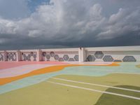 the sky is dark and cloudy over the large building and wall paint that was painted by children