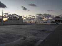 an empty parking lot with buildings in the background under a cloudy sky at dusk in florida