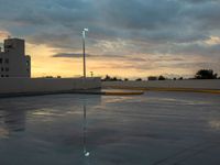 a parking lot in front of an industrial building at sunset with the sky reflecting off of it