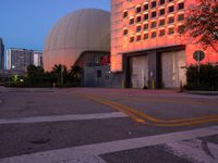 a building is illuminated up at night with a dome next to it in the background